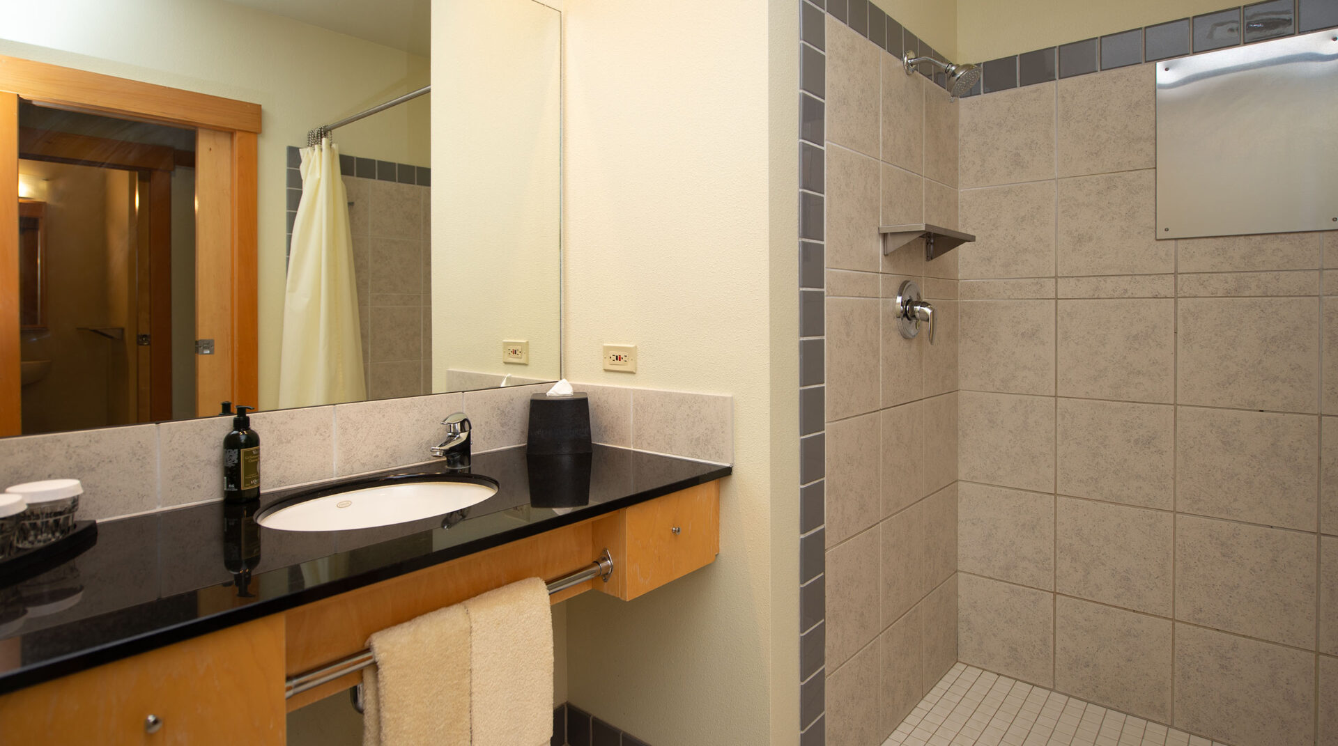 A bathroom at Chrome lake with a tile shower and black marble countertops